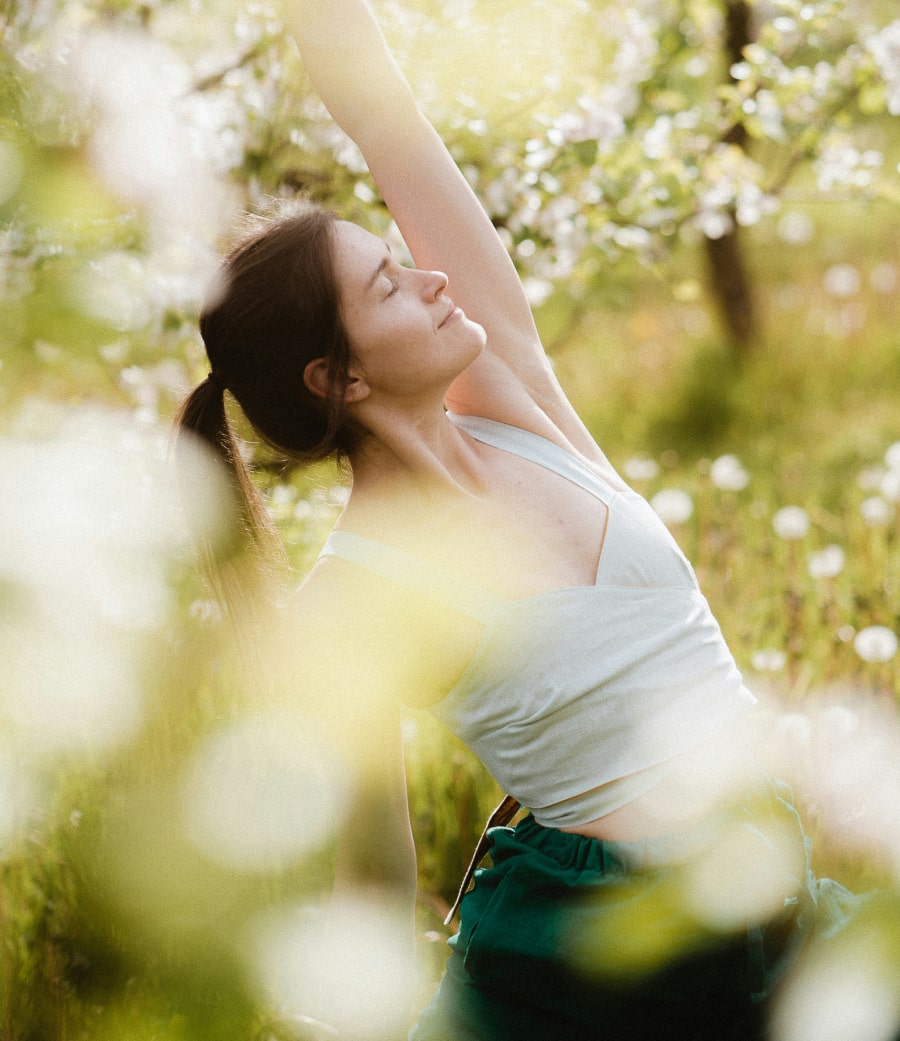supporting you in achieving. woman stretching amongst trees